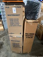 Boxes labeled as 12 packs of Continental 2818 wastebaskets with color codes and model numbers, including green, blue, and black wastebaskets. One black wastebasket visible on top of a box.