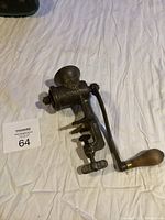 Antique cast iron manual grinder with wooden handle lying on a white surface showing the front and clamp base