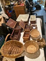 Photo of the collection of baskets laid out on a table, showcasing various sizes and materials including wicker, wooden slats, and fabric-lined baskets.