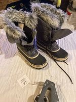 Pair of tall women's winter boots with grey faux fur at top and black waterproof lower section, size labels inside.