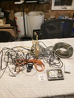Photo of the lot on a table showing numerous tangled electronic cords and cables in various colors including black, yellow, gray, and orange. Also visible is a Western Digital hard drive and a white device with sockets and plugs.