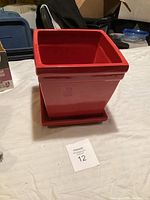 Red square ceramic planter with matching saucer, shown from two angles on a table.