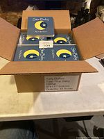 Open cardboard box containing multiple copies of the Star Baby kids book by Tally Dufour showing the front blue cover with moon and star graphic.