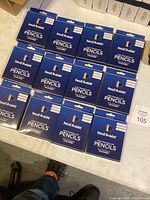 Twelve boxes of Pencil Buddies kids triangular pencils arranged on the floor, each box is blue with white text.