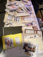Lot of assorted vintage sewing patterns laid out on a bed showing various envelopes and pattern sheets.