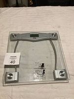 Top view of glass digital bathroom scale placed on a beige cloth background.