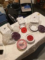 Photo showing various ceramic serving ware including mini brie bakers, bowls with lids, and boxed items on a table.