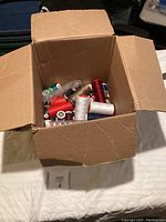 Wide angle photo of open cardboard box filled with multiple sewing thread spools in assorted colors.