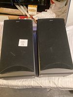 Front view of two black Sony bookshelf speakers placed side by side on a white surface.
