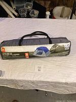 Photo of the Ozark Trail 3 Person Dome Tent packed in carrying bag on white sheet, showing size and brand.