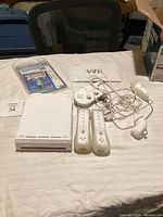 Overall photo showing Nintendo Wii console, controllers, manual, and game magazine on a white surface