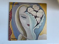 Front cover of the vintage Derek & The Dominoes vinyl album showing surreal artistic illustration of a woman's face with flowers, signed by artist.