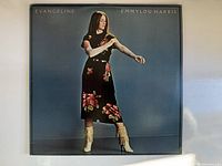 Front cover of the Emmylou Harris Evangeline vinyl album showing the artist in a floral dress and boots against a blue background