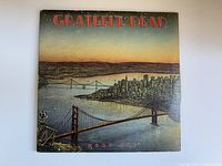 Front cover of Grateful Dead Dead Set album showing sunset city skyline and Golden Gate Bridge with skeleton figure.