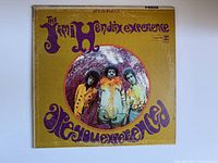 Front cover of vinyl album showing yellow background, purple text, and photo of band members in colorful clothing.