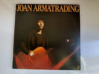 Front cover of vintage Joan Armatrading album showing artist with guitar and orange light effects.