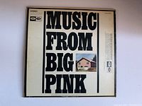 Front cover of the album Music From Big Pink by The Band, showing large black text and a small photo of a house.