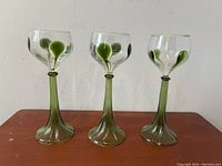 Front view of three Bohemian Jugendstil Art Nouveau wine glasses with emerald green spun glass stems, showing the overall height and design.