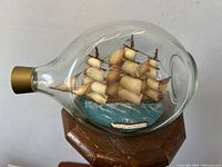 Front view of glass bottle housing the ship model and ocean base inside.