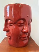 Front view of the four-faced ceramic Buddha plant stand with carmine red glossy glaze.