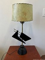 Full view of the mid-century modern table lamp showing the parchment shade with visible age wear and the black wooden geometric accents on a wooden base