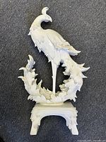 White resin Asian phoenix bird sculpture, front view showing entire piece on dark carpet background.
