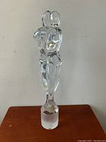 Full front view of the clear Murano glass sculpture depicting two nude lovers in an embrace, standing on a frosted cylindrical base.