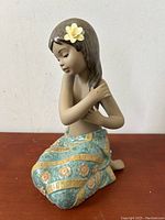 Front view of seated figurine showing full pose, flower detail and skirt pattern