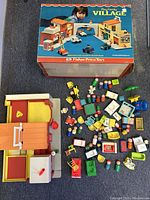 Photo of the main village building with all the small figures and accessories arranged around it on carpet.