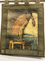 Detailed closer angle of the artwork showing the subject's muscular back, arm and the decorative border edges with hanging loops.