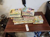Photo of multiple stacks of Archie comic books on a wooden table, showing the quantity and general condition of the lot.