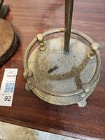 Close-up photo of the brass umbrella stand base showing patina and wear.