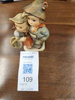 Front view of Hummel No. 94 figurine showing two children, boy and girl, with the boy holding something behind the girl.