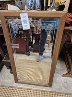 Full view of a rectangular mirror showing the wooden frame and etched floral design in the corners.