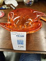 Front angled view of the orange chalet glass dish showing its flowing design and clear pedestal base.