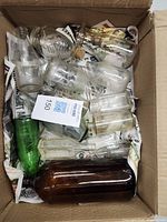 Top view of a cardboard box containing 13 vintage glass bottles of different colors and sizes packed with newspaper.