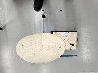 Top view of the oval cream weighing pan on the vintage cast metal scale showing paint wear and marks.