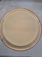 Top view of a single metal pie plate, round with cream interior and red rim showing wear.