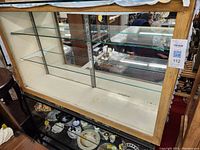 Front and interior view of the wooden cabinet showing glass shelves and backing, some shelf support hardware, and overall structure.