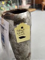Steel shell casing from WW1 with visible rust and a yellow tag labeled 'Steel Shell WW1'.