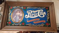 Framed Pepsi-Cola sign with Gibson Girl and advertising text.