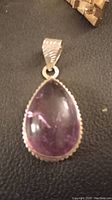 Front view of the teardrop-shaped ametrine gemstone pendant set in bezel .925 silver setting on dark surface.