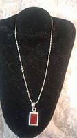 Front view of necklace on black display bust showing the red jasper square pendant and beaded silver chain.