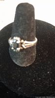Front view of the .925 sterling silver ring with a central sapphire stone displayed on a black ring holder.