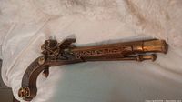 Cast metal flintlock pistol ornate wall decor lying on fabric