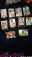 Top view of 11 vintage baseball cards in protective sleeves showing headshots and player names.
