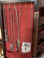 Seven necklaces hung on red display showing full set