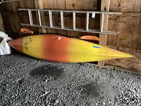 Full side view of kayak stored against wall with ladder behind