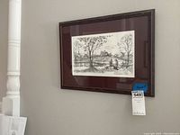 Framed art hung on a wall showing overall piece including the frame and glass.