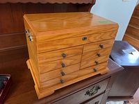 Photo of closed wood jewelry box showing medium wood finish, seven drawers, and metal knobs.
